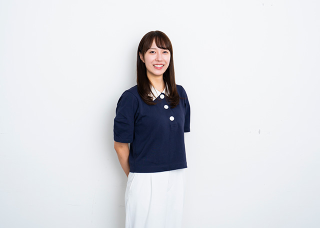 手を後ろに組んで微笑むRIE