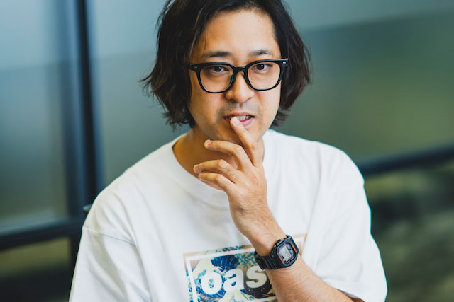 口に手を当てながら真剣な表情で話す金澤