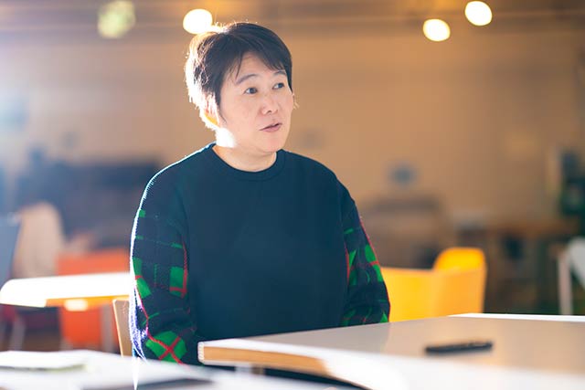 袖に赤と緑のアーガイルの模様がある黒いニットを着た藤平裕子